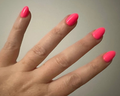 Hand with pink nail polish on a plain background
