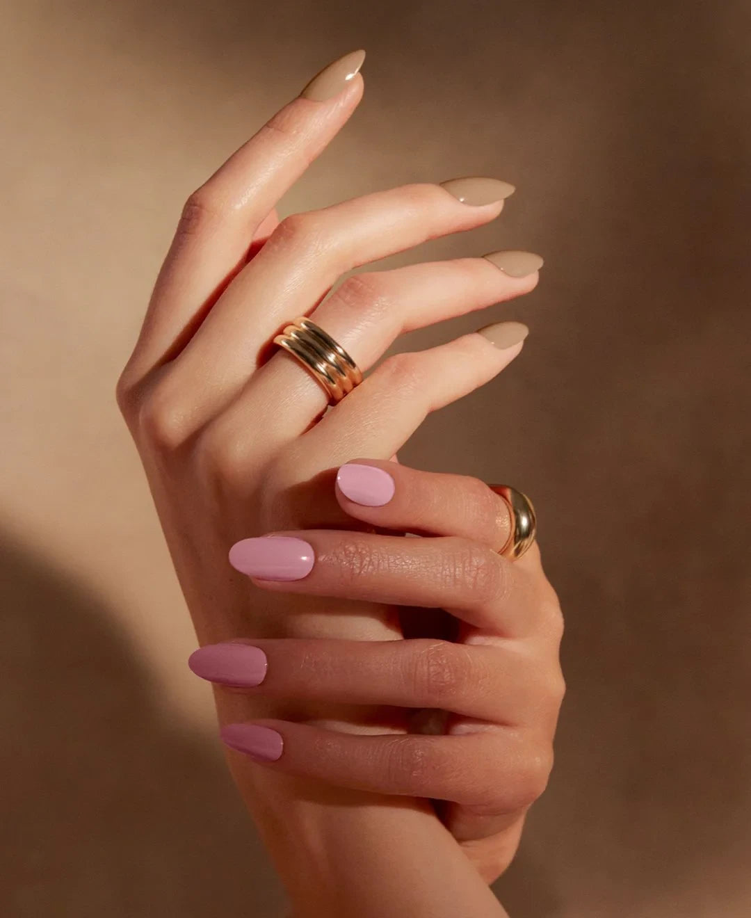 Close-up of hands with glossy pink and nude shellac nails and a smooth oval shape