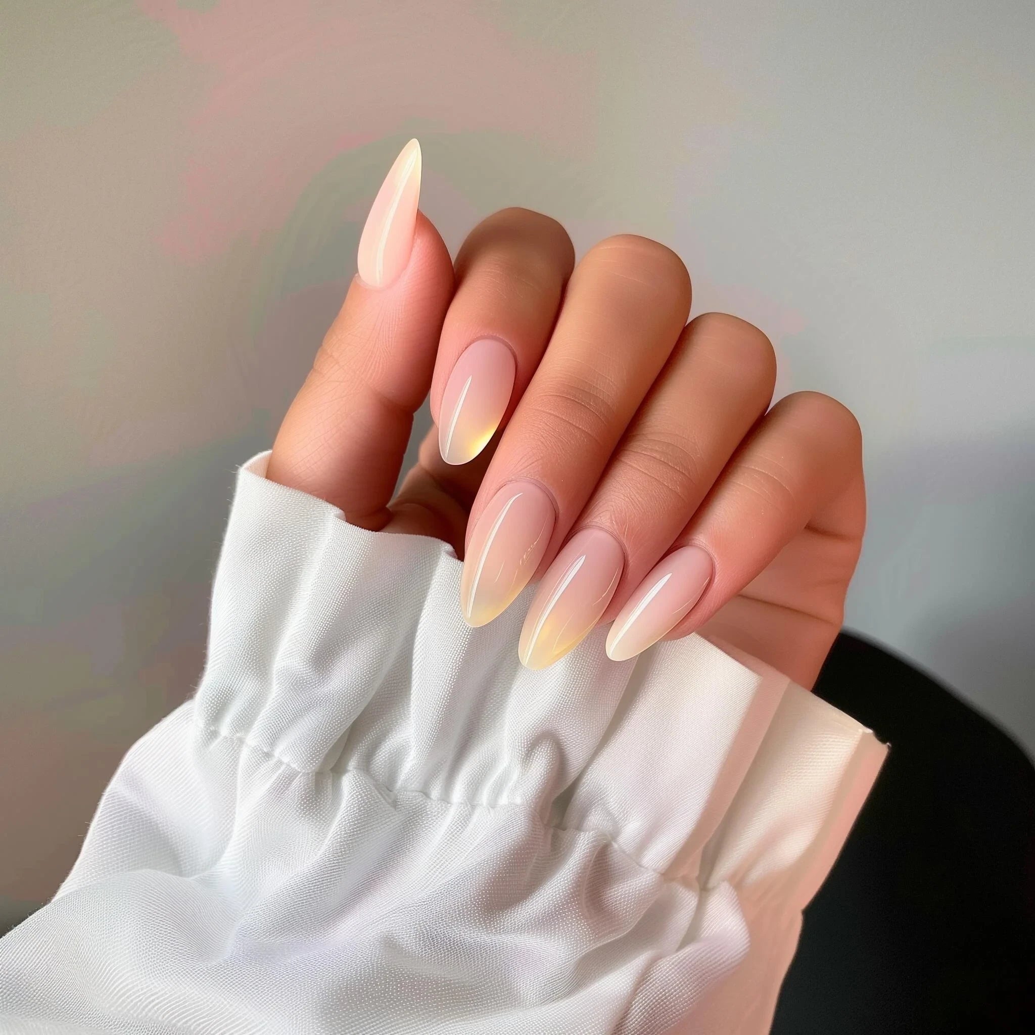 Close-up of natural almond-shaped false nails with a glossy nude finish