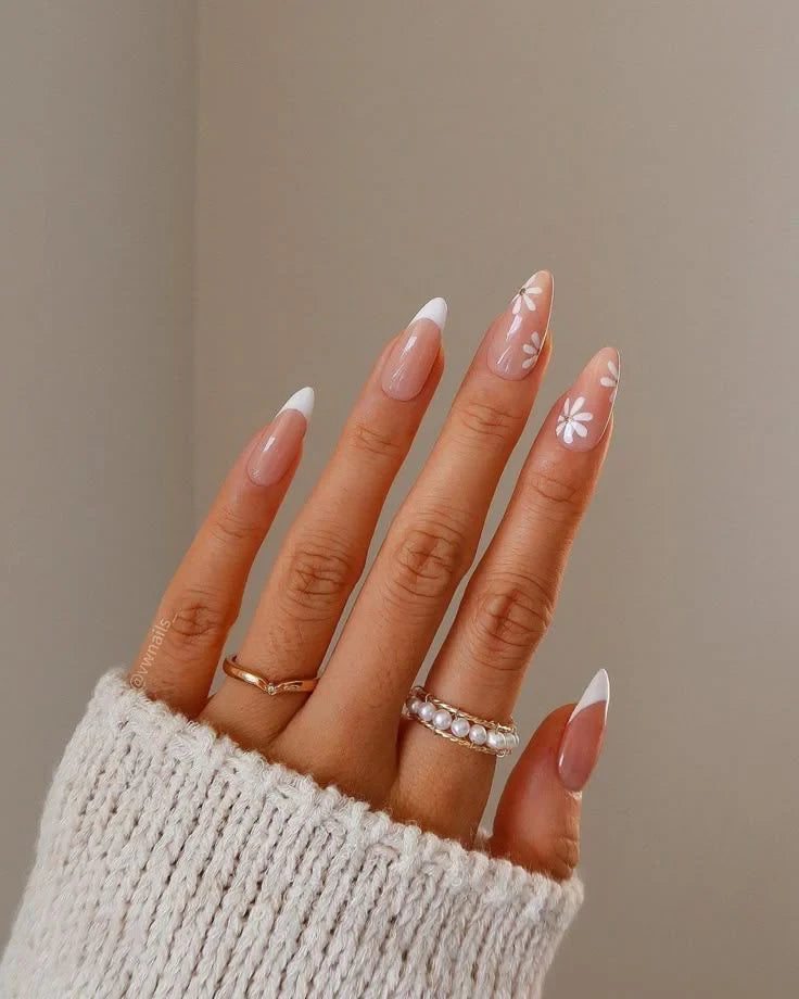 Close-up of almond-shaped nails with white French tips and minimalist flower nail art
