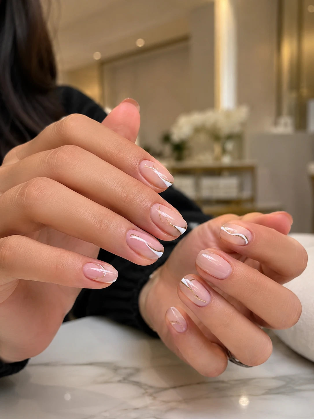 Close-up of nude nails with abstract white French tips and gold line nail art near Croydon